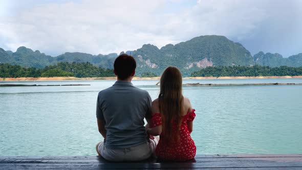 Couple on Date Sit Together on Lake Bridge and Woman Puts Head on Shoulder