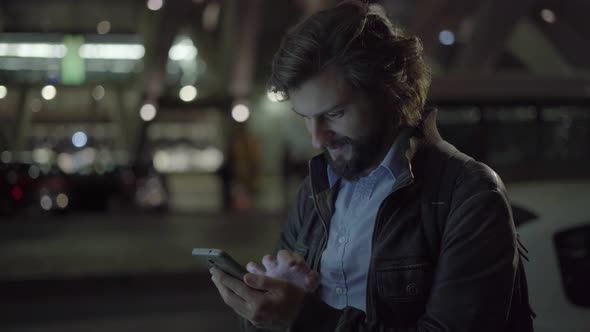 Happy Man Texting on Smartphone at Night in Urban City