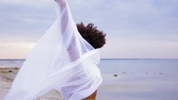 African Woman with Shawl Waving in Wind on Beach 