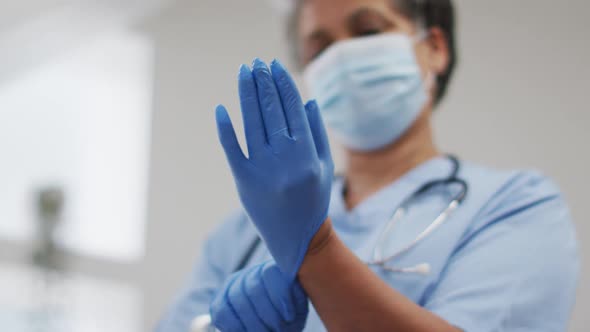 Senior african american female doctor wearing face mask putting protective gloves on