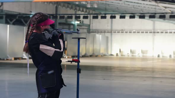 BULLET SHOOTING. Girl in a Pink Cap Is Reloading a Gun