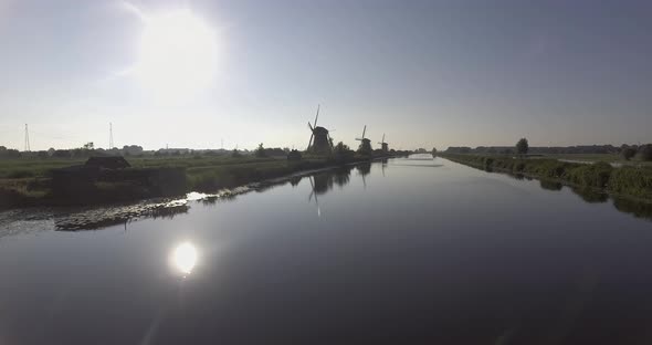 A drone shot panning backwards, around Dutch Windmills during sunrise