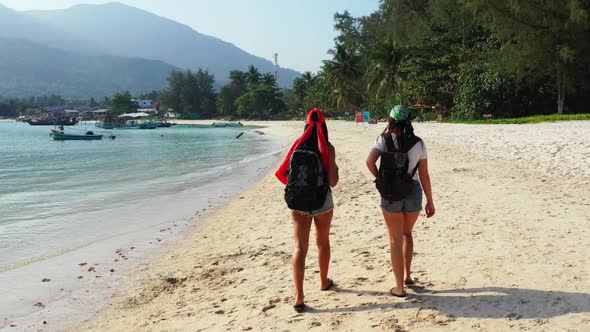 Female models best friends on paradise coastline beach time by blue ocean with white sandy backgroun