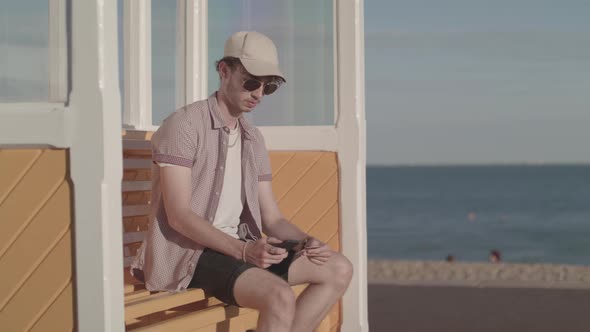 Man Sat on Bench Near Sea Uses His Phone and Credit Card To Make A Purchase Online - Ungraded