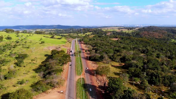 A scenic highway through the green summer countryside - pull back aerial view