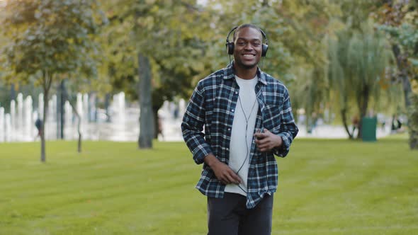 Happy Active Cheerful African American Guy Student Teenager Wears Headphones Walking Going Stepping