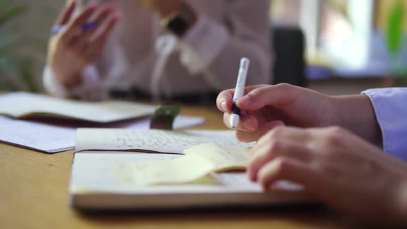 A Female Hand Writing Notes in Notepad