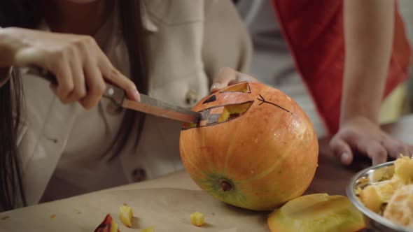 A Cute Young Lady is Carving a Mouth of a Pumpkin