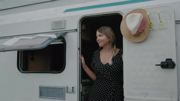 Smiling woman enjoyng vacation and standing in motor home RV campervan.