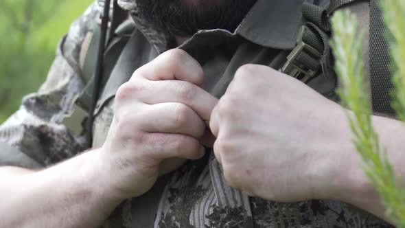 Slow Motion Close Up Shot of Fisherman Fastens Button on a Shirt. Tourist in Camouflage with