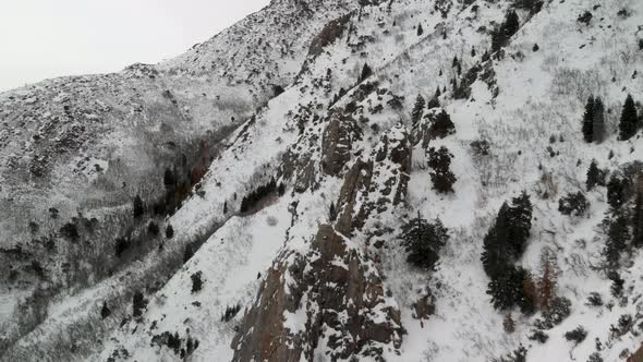 Aerial view traversing up snow-covered Grandeur Peak in Utah.