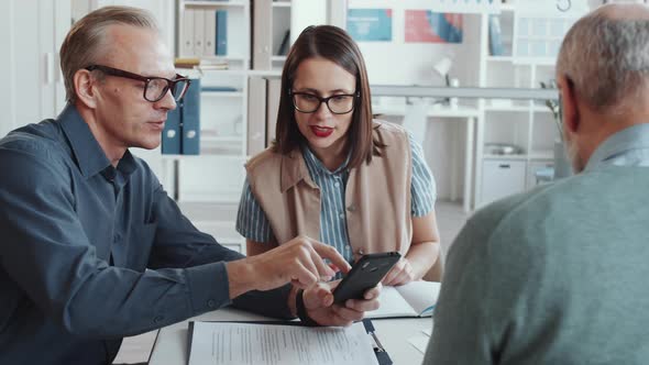 Male and Female Coworkers Using Smartphone and Speaking at Office Meeting