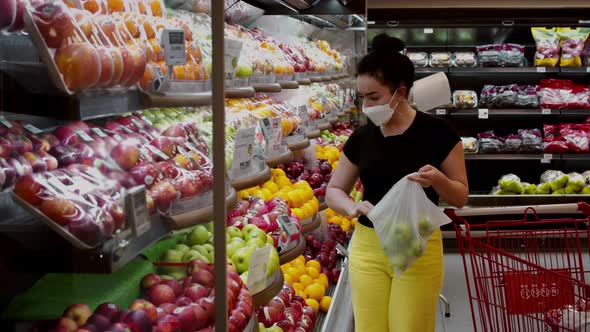 Young Woman in a Mask From a Coronavirus Epidemic is Standing in the Grocery Department of a