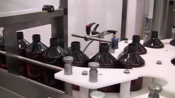 Factory conveyor spinning and filling bottles. Automatic process of filling bottles.