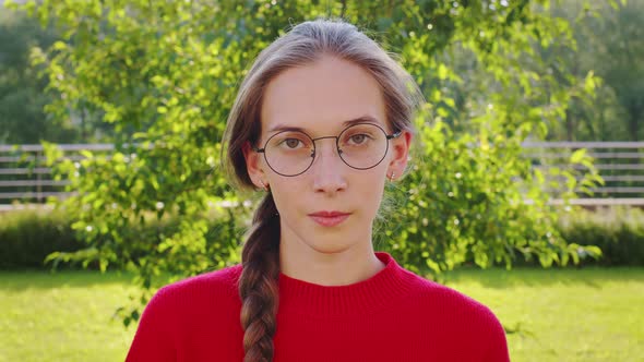 Girl with Plait in Glasses Looks at Camera Smiles