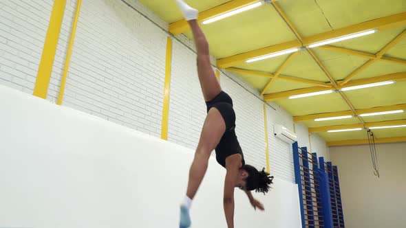 Female Athlete Making Cartwheel Exercise on Mats in Gym