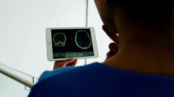 Beautiful surgeon examining report on digital tablet