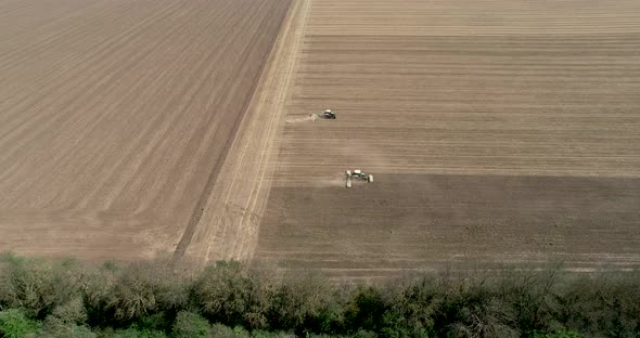 Aerial view two tractors working on the field.