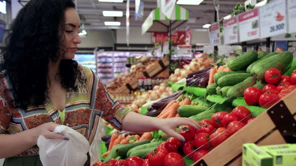 Young Woman Housewife in a Grocery Store Buys Takes Ripe Tomatoes From the Shelf and Puts Them in a