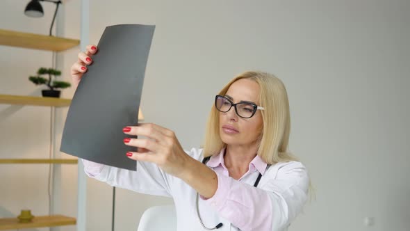 Senior Female Doctor Examining an Xray of the Lungs of a Covid 19 Patient