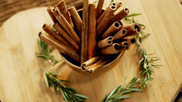 Cinnamon sticks and rosemary arranged on wooden board