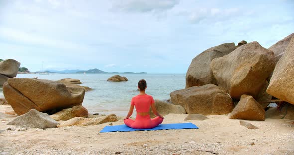 Bach Shot of a Woman She Seats in Meditation Pose By the Sea Line on Blue Yoga Mat