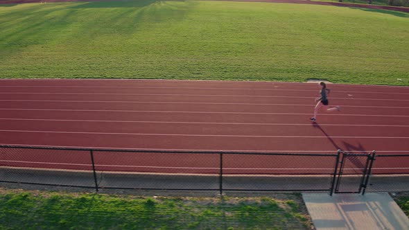 a teen girl track athlete runs track as camera tracks left