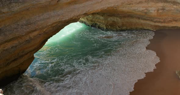 A Large Hole Inside of a Rocky Cliff Covered with Foamy Tide Seen From the Top