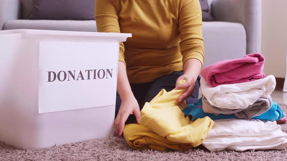 Closu up of woman selecting clothes for donation and putting them in a box. Concept campaign to dona