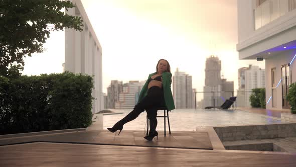 Woman In Bra And High Heels Sitting And Dancing On Poolside Chair