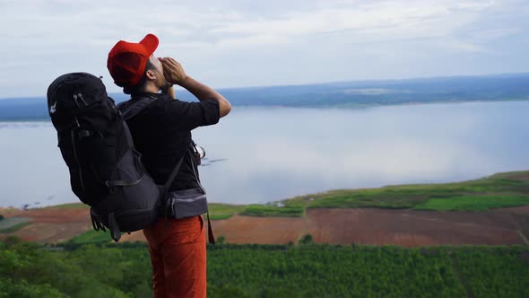 cheerful hiker man shouting and arms raised on the edge of a cliff