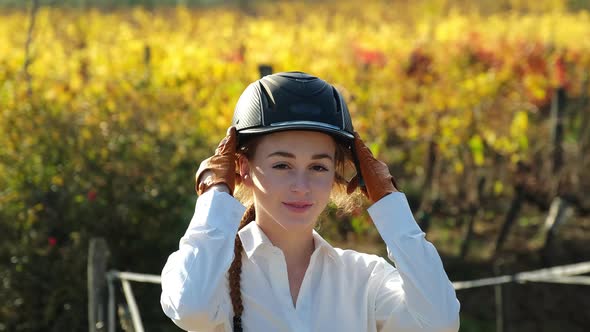 Young female rider putting on riding helmet