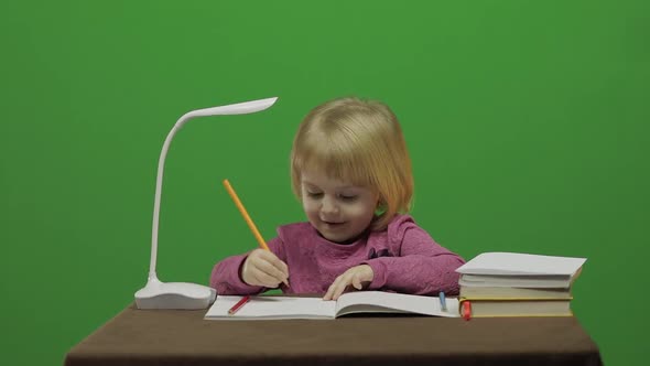 Girl Drawing at the Table. Education Process in Classroom. Chroma Key