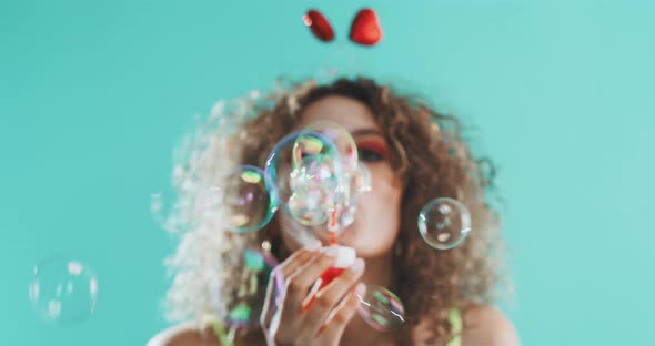 Girl blowing bubbles while dacing and smiling at the camera