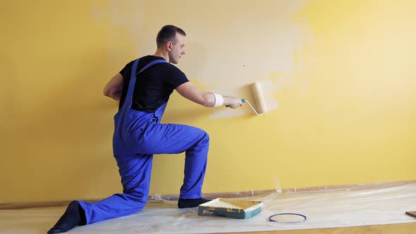 Young man painting wall with roller brush while renovating his apartment.