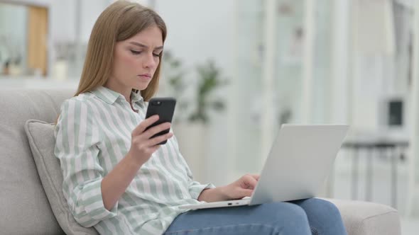 Young Woman Using Smartphone and Laptop at Home