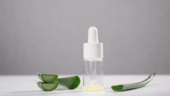 Fresh Aloe Juice in Glass Bottle on Table Near Cut Leaves