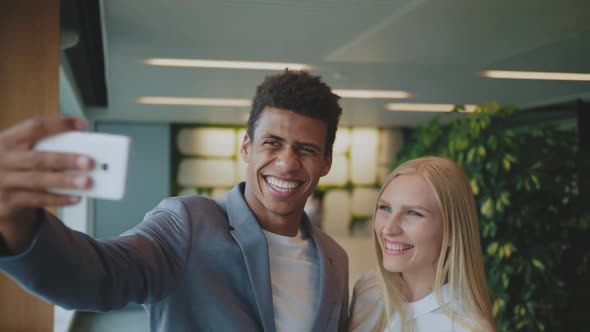 Laughing Diverse Coworkers Taking Selfie in Office. Cheerful Black Man with Laughing Blond Woman