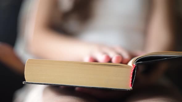 Girl leafing through a page of a paper book, close-up