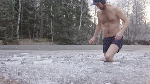 A trendy ice bather steps into the ice hole and begins his cold water exposure