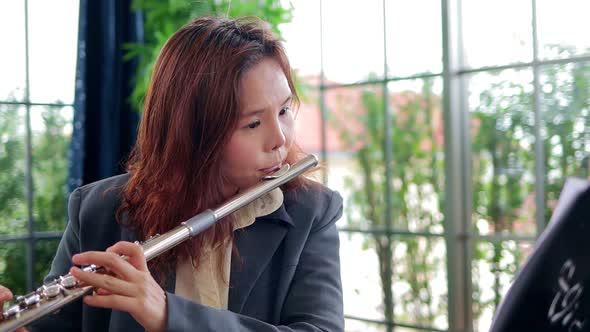 Asian woman teacher in business suit she teaches classical music Playing the flute