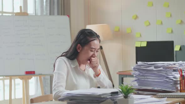 Tired Asian Woman Yawning While Working Hard With Documents At The Office