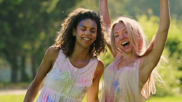 Two Girls Covered in Paint Smiling Posing for Cam at Color Festival