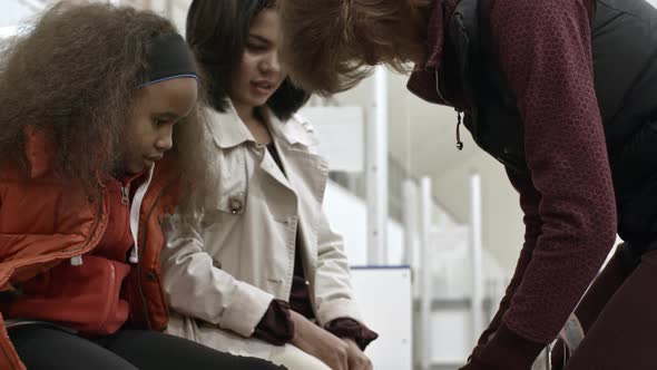 Coach Helping Girl to Tie Ice Skates