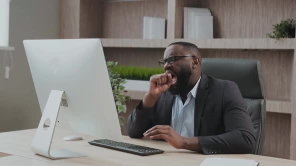 Tired African American Male Worker Yawn Stretch in Office Chair Overwhelmed with Work at Workplace