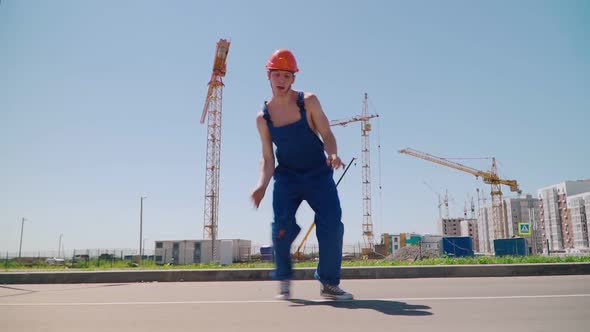 Happy Caucasian Man Builder in Hard Hat Dancing. Worker Funny Moves Background Construction Site.