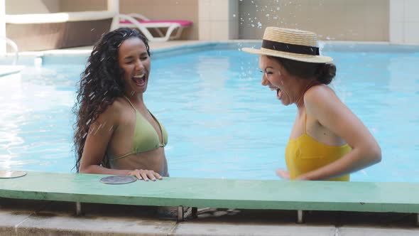 Funny Cheerful Girlfriends Splashing in Pool Having Fun During Summer Holidays