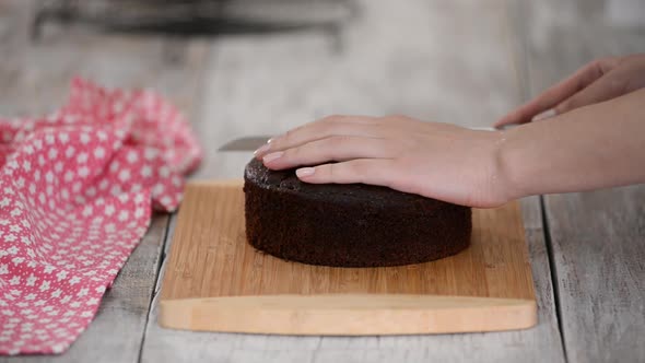 Cutting Chocolate Sponge Cake on Layers. Preparing Cake at Home