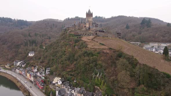 drone footage flying to cochem castle on the mountain covered with vineyards next to the moselle riv