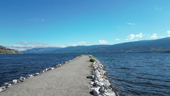 Fast motion fly over a path that extends out into Okanagan Lake.